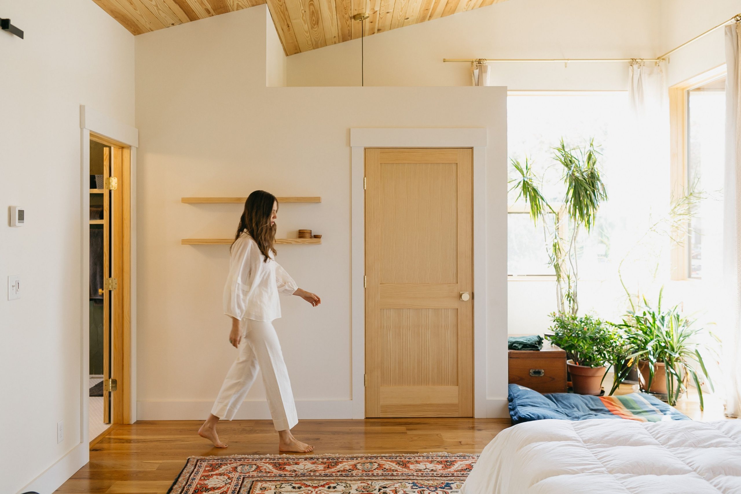 Interior bedroom design inside of an Asheville home, featuring large carpets, plants, and sunlight
