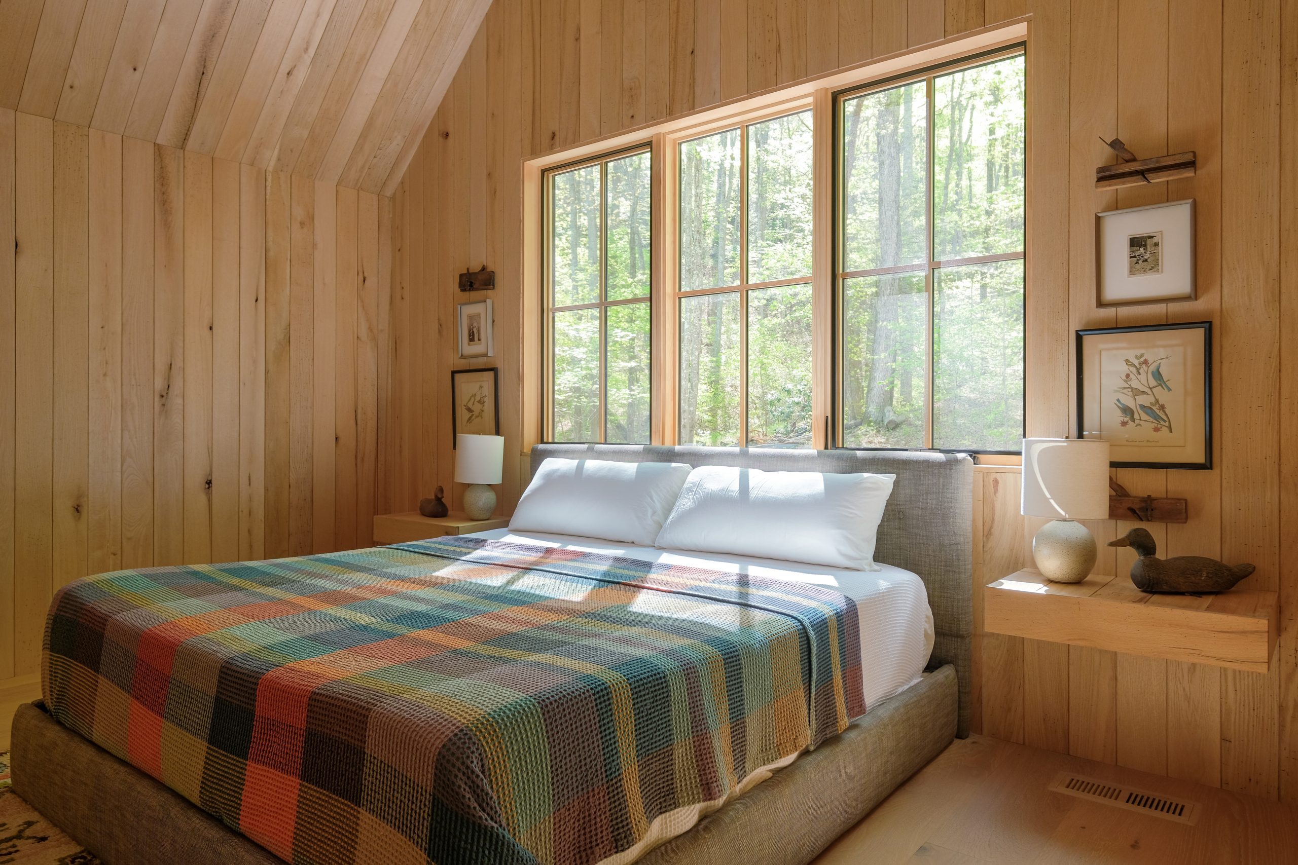 a frame ceiling bedroom with windows facing forest view