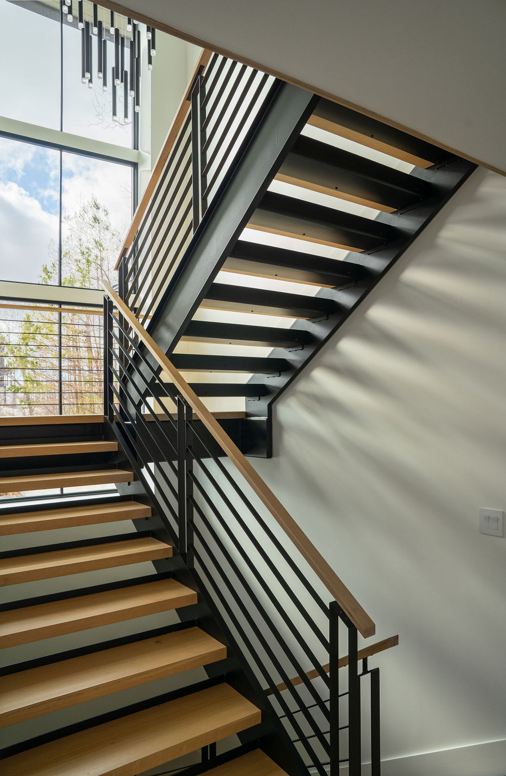 A floating staircase with thick butcher-block treads and a central steel stringer, crafted in a contemporary Asheville home to act as a sculptural centerpiece. 